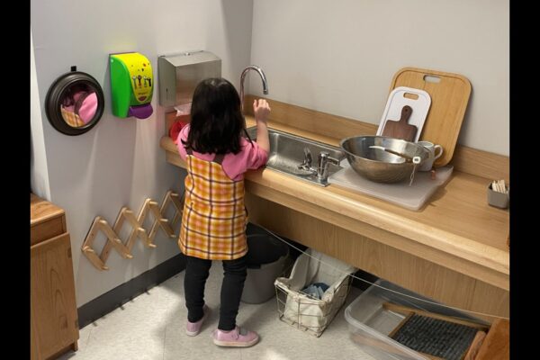 A Montessori student is washing dishes in the kitchen
