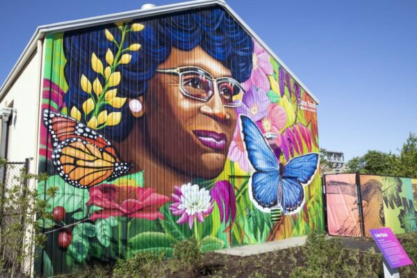 Colorful mural of a woman’s portrait surrounded by flowers and butterflies on a farm house wall